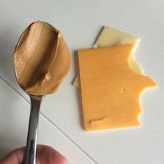 a spoon full of peanut butter next to a piece of cheese