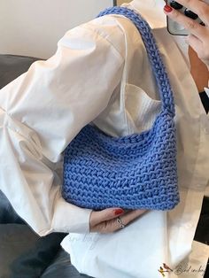 a woman is holding a crocheted blue purse