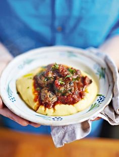 a person is holding a plate with food on it and sauce in front of them