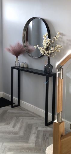 there is a vase with flowers and a mirror on the wall next to the stairs