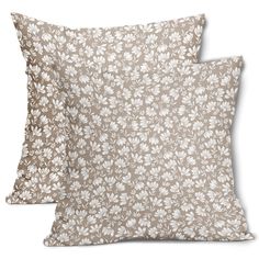 two pillows with white flowers on them, one is brown and the other is beige