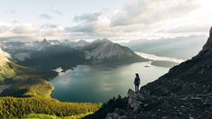 a person standing on top of a mountain overlooking a lake