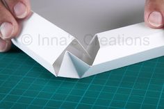 someone is cutting out an origami box with scissors and paper on the table