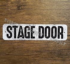 a sticker that says stage door on a wooden surface with the word's name