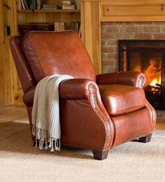 a brown recliner chair sitting in front of a fire place with a blanket on it