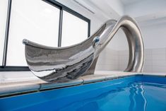 a metal sculpture sitting on top of a blue swimming pool next to a large window