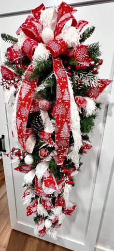 a red and white christmas wreath hanging on the front door