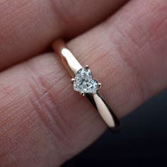 a close up of a person's hand holding a ring with a diamond in it