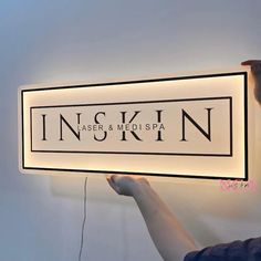 a person is holding up a sign that says inskin laser and medispa