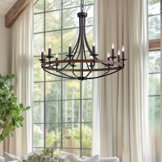 a chandelier hangs from the ceiling in front of a window with drapes