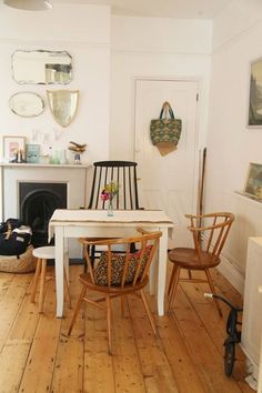 two chairs and a table in a room with wood floors, white walls and fireplace