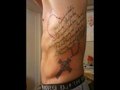 a man with a cross tattoo on his chest and words written in the middle of it