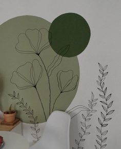 a white chair sitting in front of a wall with flowers and leaves painted on it