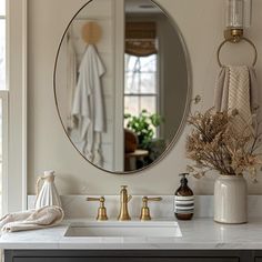 a bathroom sink with a round mirror above it