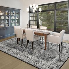 a dining room table with chairs and a rug on the floor in front of it