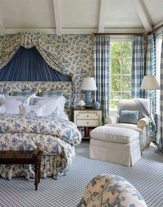 the bedroom is decorated in blue and white with floral bedding, chairs, and lamps