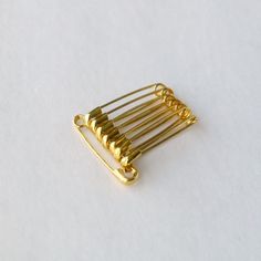 a gold hair comb on a white background with clippings in the shape of squares