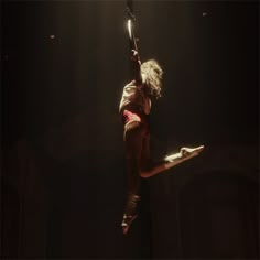 a woman is suspended in the air on a pole with her arms extended and legs spread out