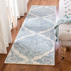 a white bench sitting on top of a hard wood floor next to a blue rug