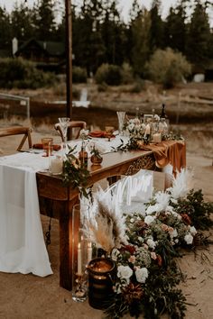 a long table with candles and flowers is set up in the middle of an open field