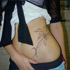 a woman's stomach with a tattoo on the side and an open tie around her waist