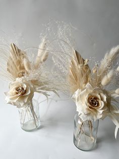 two vases with flowers and feathers in them