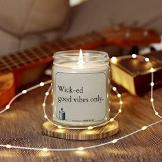 a candle sitting on top of a wooden table next to a guitar and string lights