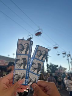 two people holding up tickets in front of a crowd