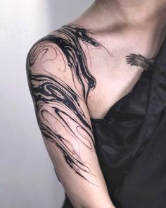 a woman's arm with black ink on it and a bird flying over her shoulder