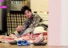 a young man sitting on top of a pile of clothes in front of a mirror