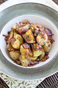 a white bowl filled with potatoes covered in bacon