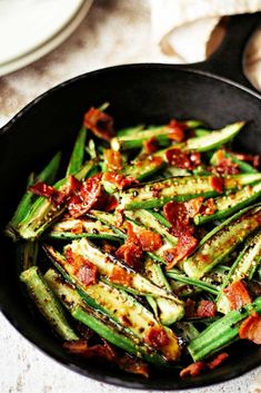 cooked green beans and bacon in a skillet on a table with other food items