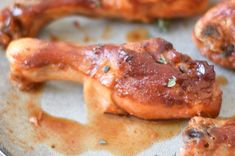 some chicken wings are covered in sauce on a metal pan with green sprinkles