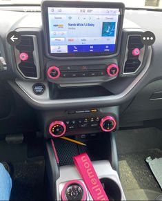 the interior of a car with pink and black trims, steering wheel controls and dash stickers