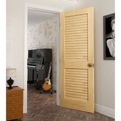 an open door in a room with a guitar on the floor and wallpaper behind it