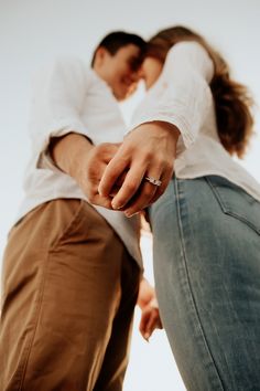 a man and woman holding hands while standing next to each other in front of the camera