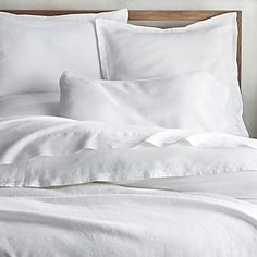 a bed with white sheets and pillows on it