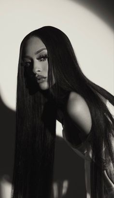 a black and white photo of a woman with long hair in the shadows, looking at the camera