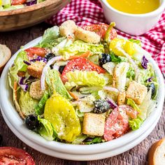 a salad in a bowl with dressing and bread on the side, ready to be eaten