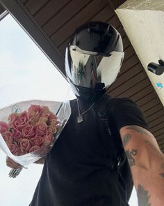 a man wearing a helmet and holding a bouquet of roses in front of his face