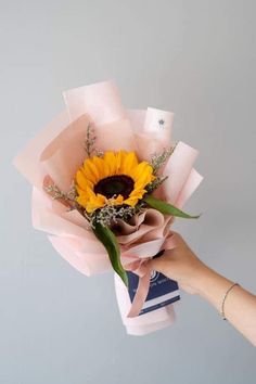 a person holding a bouquet of flowers in their hand with the sunflower on top