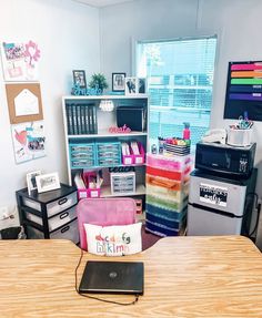 a room with desks, shelves and other office supplies on the table in front of a window