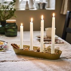 there are many lit candles in the tray on the table with other food items around it