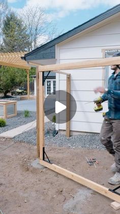 a man standing in front of a house holding a drill and screwdriver while working on the frame