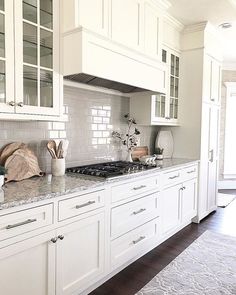 a kitchen with white cabinets and marble counter tops