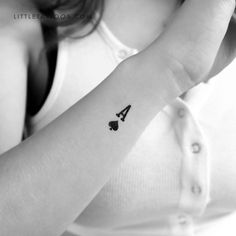 a woman with a small tattoo on her arm holding up the letter a in front of her face