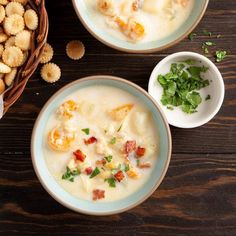 two bowls filled with soup and crackers on top of a wooden table next to each other