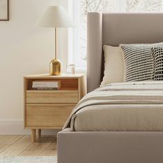 a bedroom with a bed, night stand and two lamps on either side of the bed