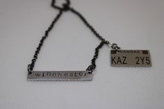 two necklaces that say winchester and kaz, hanging from a black beaded chain