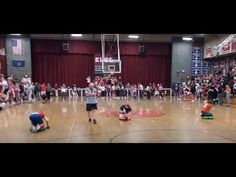 children playing basketball in an indoor gym with people watching from the sidelines and onlookers